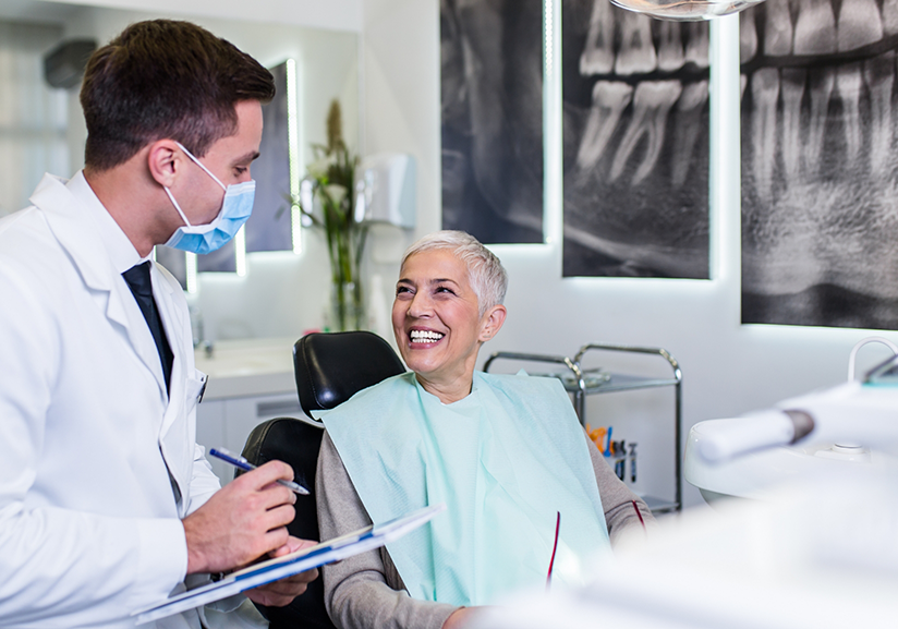 Patient sitting and smiling up at dentist