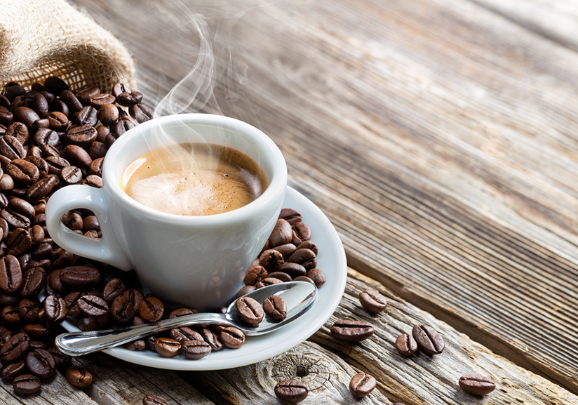 Cup of coffee on plate surrounded by beans