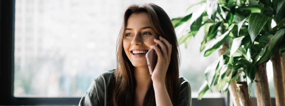 Woman sitting in front of plant talking on phone