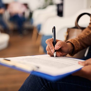 Person filling out paperwork on clipboard