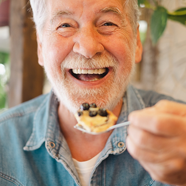 Senior man eating dessert with a spoon