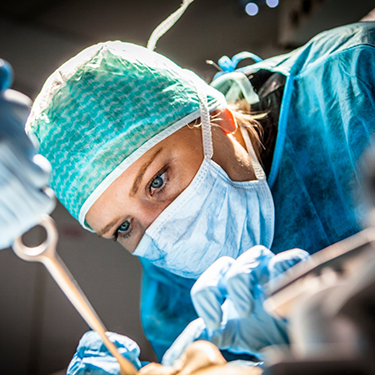 Dentist with mask performing dental implant surgery