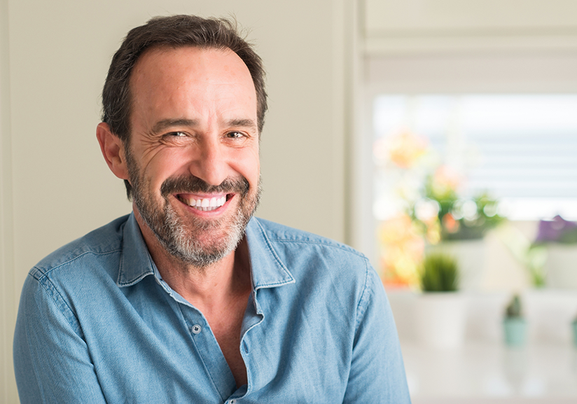 Man in button up shirt smiling near window