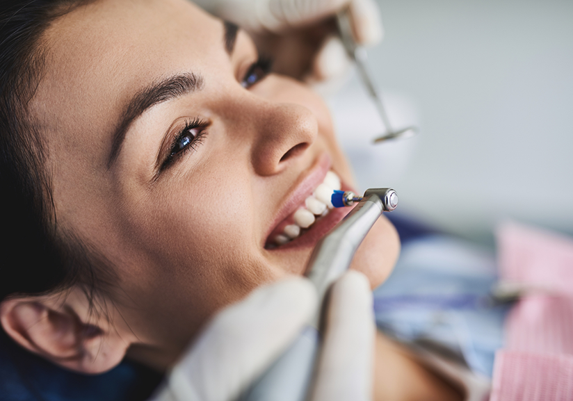 Close-up of woman having teeth cleaned at dentist's office