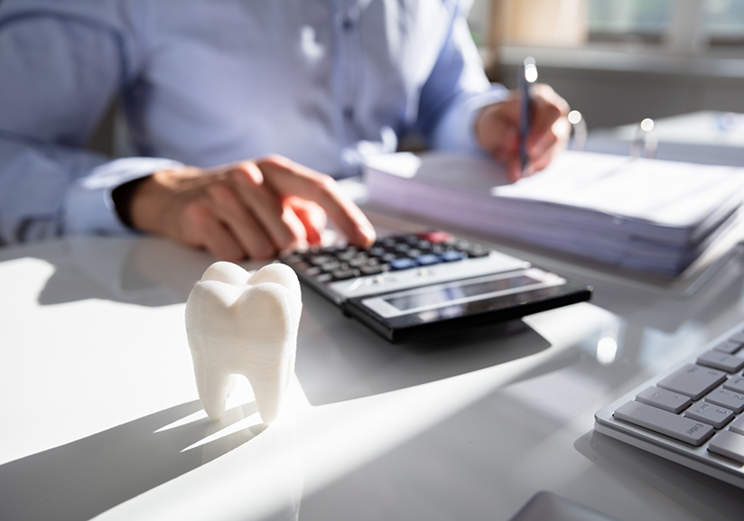 Using calculator with tooth-shaped paperweight nearby