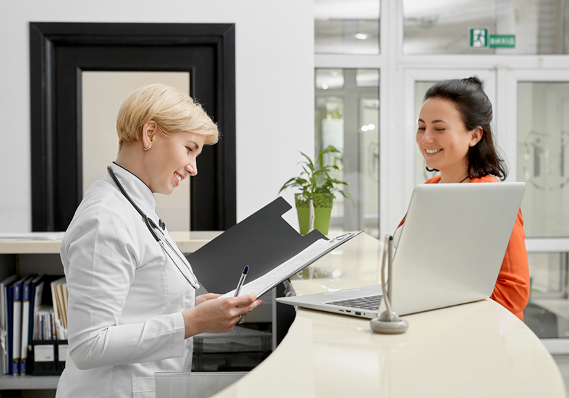 Dentist at front desk looking at paper in folder