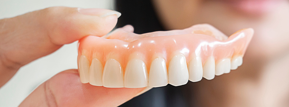 Close-up of hand holding dentures in Pantego