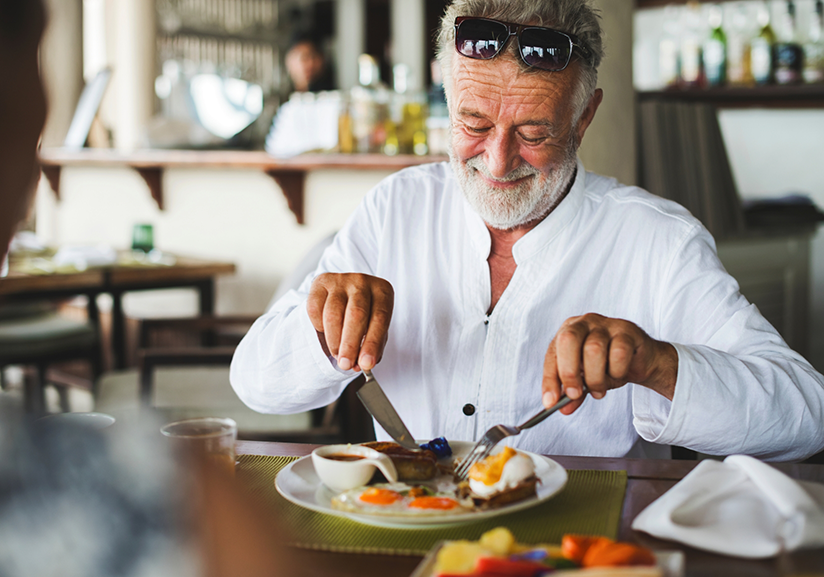 Bearded man using fork and knife to eat