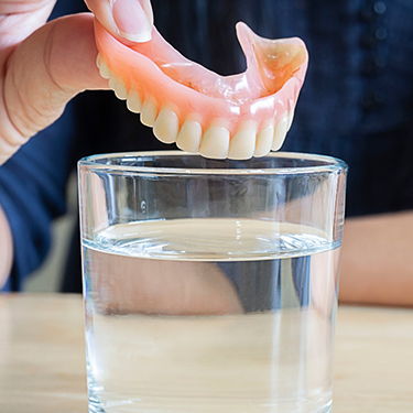 Taking dentures out of glass of water