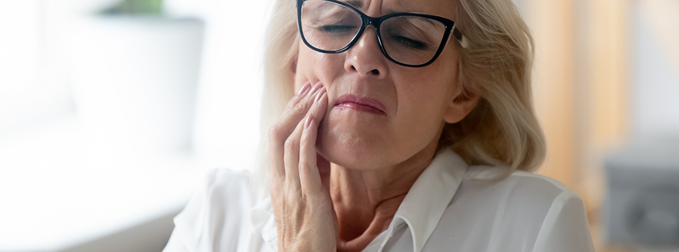 Woman with glasses rubbing jaw in pain