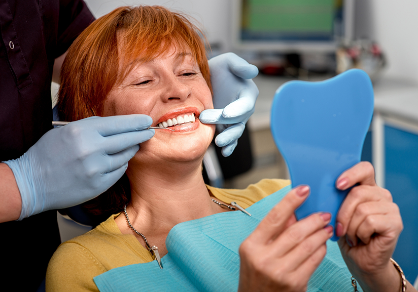 Red-haired dental patient checking smile in mirror