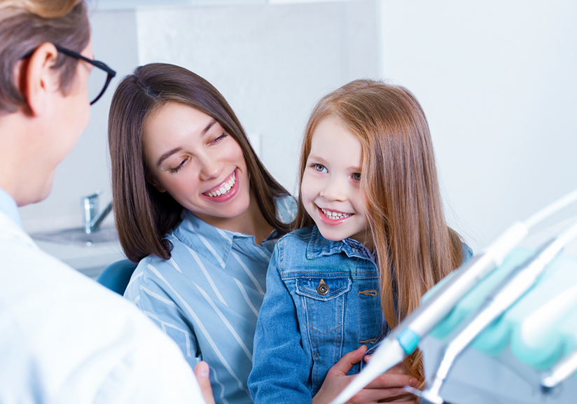 Woman sitting in dental chair holding little girl