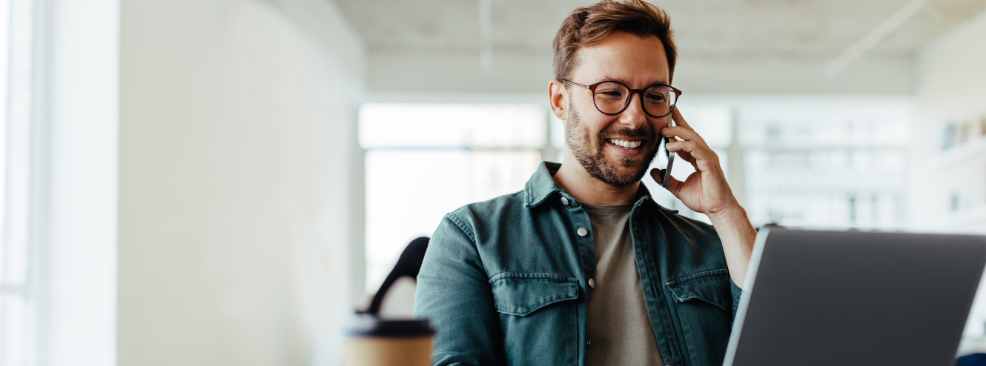 Man sitting at laptop and talking on phone