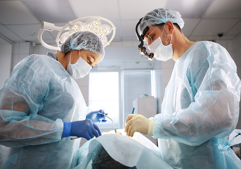 Dentists in masks performing dental implant surgery