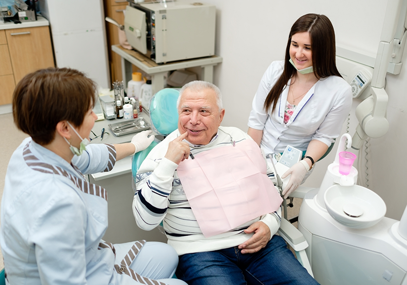 Senior man looking at dentist and pointing to mouth