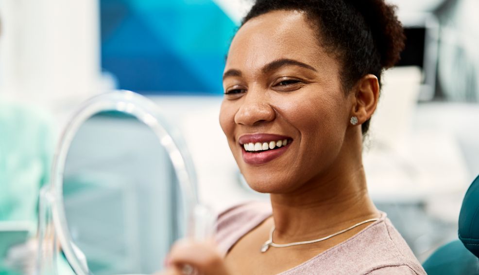 Female dental patient checking smile in handheld mirror