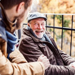 Senior man with hat talking to another man