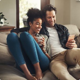 Man and woman sitting on couch looking at phone