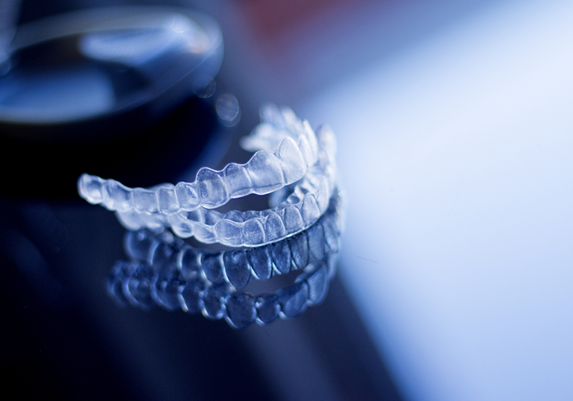 Two clear aligners sitting on a reflective surface