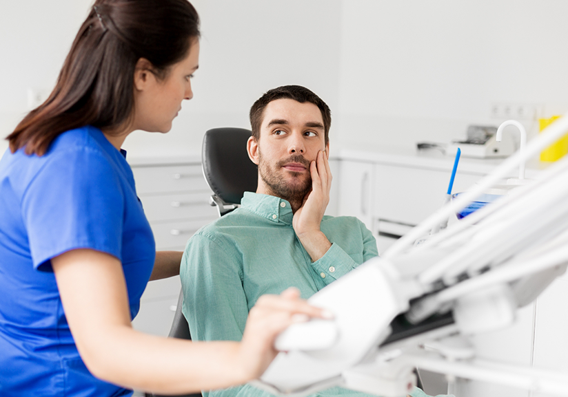 Dental patient rubbing jaw and looking at dentist