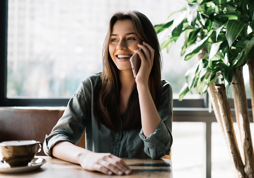 Smiling woman at table talking on phone