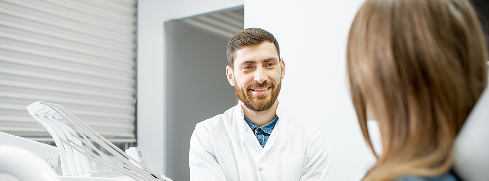 Bearded dentist talking to female dental patient