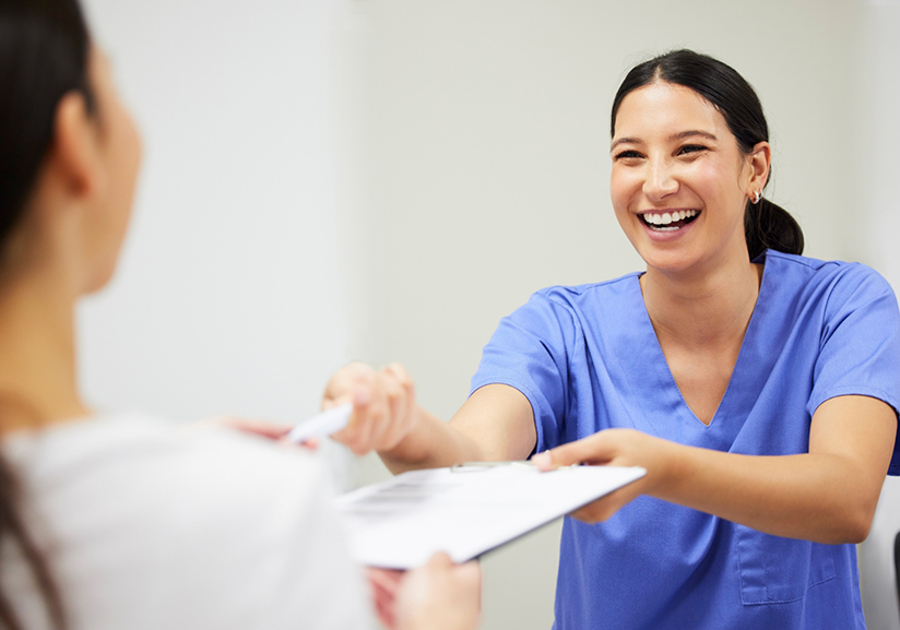 Dentist handing patient pen and clipboard