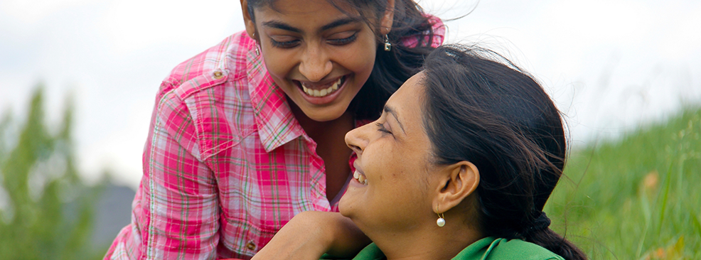 Two women in a field smiling at each other