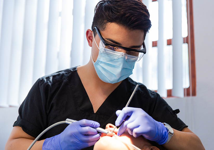 Dentist with mask performing oral cancer screening