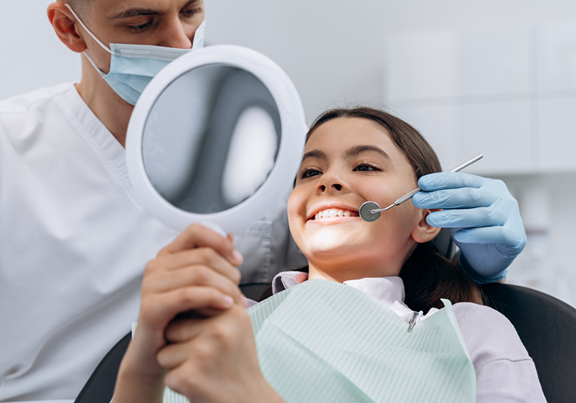 Child at dentist's office checking smile in mirror