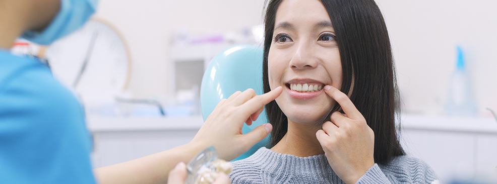 Woman in dental chair pointing to her teeth