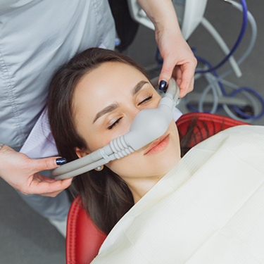 Placing mask over woman's nose for nitrous oxide sedation