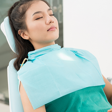 Woman in dental chair with eyes closed