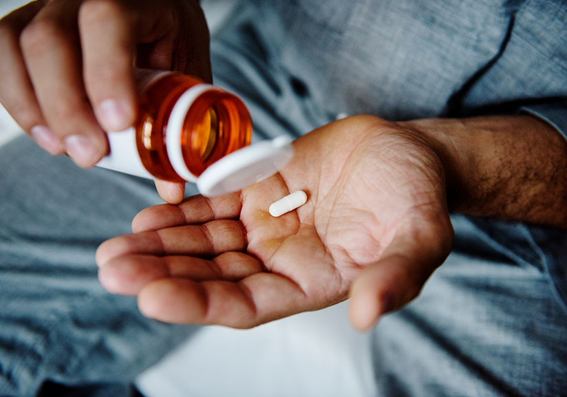 Close-up of man pouring pill into hand