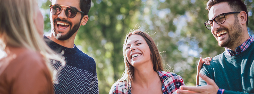 Two men and a woman laughing outside