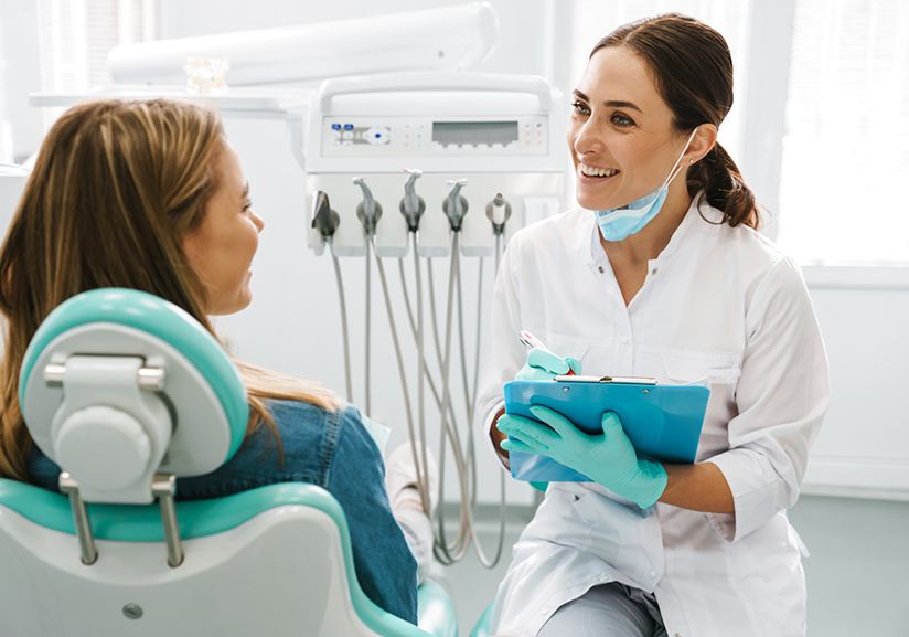 Female dentist with clipboard sitting in front of patient