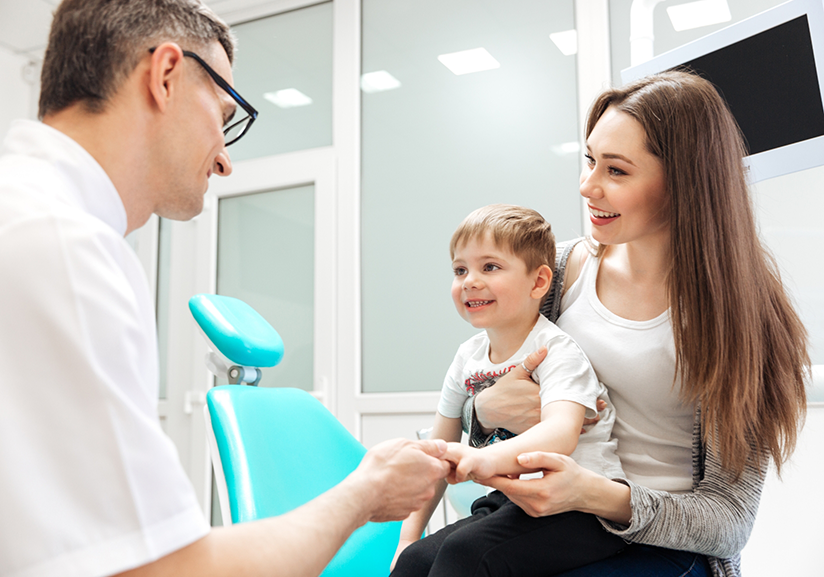 Woman holding child shaking dentist's hand