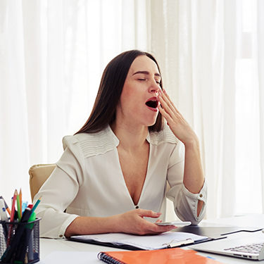 Woman sitting at table yawning