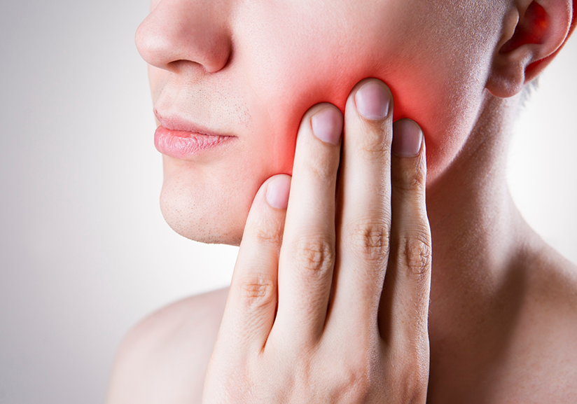 Close-up of woman rubbing jaw in pain