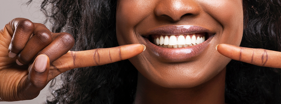 Close-up of woman pointing to her smile