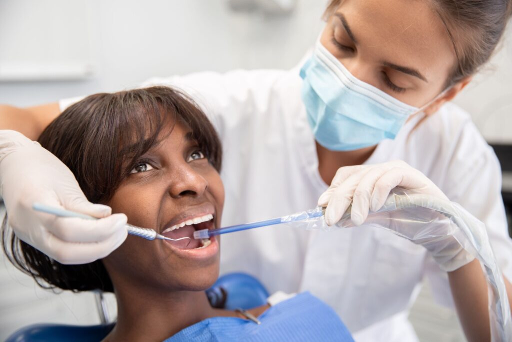 Hygienist in white gloves cleaning a woman's teeth